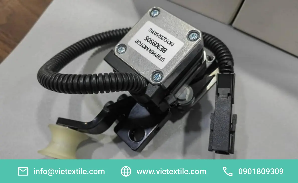 Cận cảnh Motor bước BE309505, bao gồm mô-tơ, cáp bọc xoắn, đầu nối điện và puly màu kem trên giá đỡ đen có rãnh nối.